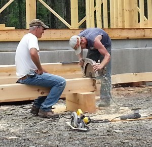 crew uses large circular saw to cut posts for post and beam project under construction, log homes, log cabins, log cabin kits, Timberhaven, post and beam cabin, post and beam cabin kits, kiln dried, laminated