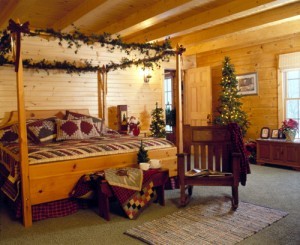 bedroom of log home decorated for Christmas, timberhaven log homes, log homes, log cabin kits, log cabins, Merry Christmas, stone fireplace, fireplace in dining room, natural light, white pine