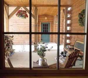 looking through the window at front porch of log home, timberhaven log homes, log homes, log cabin kits, log cabins, Merry Christmas, stone fireplace, fireplace in dining room, natural light, white pine