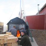 waste material being loaded into an outdoor wood burner, Timberhaven Log Homes, log homes, log cabin homes, log cabins, post and beam homes, timberframe homes, timber frame homes, laminated logs, engineered logs, floor plan designs, kiln dried logs, nature friendly