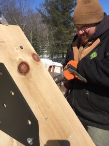 building drilling gusset plate onto King Post Truss, outdoor living area, Timberhaven Log Homes, log homes, log cabin homes, log cabins, post and beam homes, timberframe homes, timber frame homes, laminated logs, engineered logs, floor plan designs, kiln dried logs, Flury Builders, Joe Walsh, Timberhaven local reps, log homes in Massachusetts, log homes in Rhode Island, MA, RI, log home builders