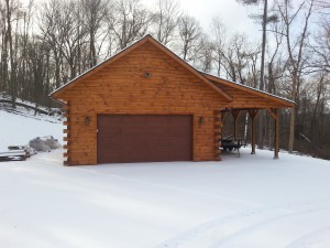 garage with log siding and snow, log siding, Timberhaven Log Homes, log homes, log cabin homes, log cabins, post and beam homes, timberframe homes, timber frame homes, laminated logs, engineered logs, floor plan designs, kiln dried logs, Flury Builders, Joe Walsh, Timberhaven local reps, log homes in Massachusetts, log homes in Rhode Island, MA, RI, log home builders