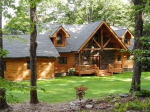 beautiful log home in wooded setting with nice lawn and stone up the front, Timberhaven Log Homes, log homes, log cabin homes, log cabins, post and beam homes, timberframe homes, timber frame homes, laminated logs, engineered logs, floor plan designs, kiln dried logs, Timberhaven local reps, log home builders, kiln-dried engineered logs, PA log homes, log homes in PA, kiln-dried engineered logs