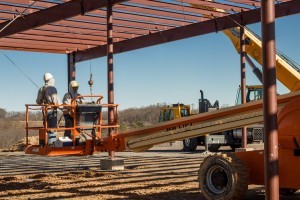 guy being lifted in air to work on steel frame, Big move, Timberhaven Log Homes, Timberhaven Log & Timber Homes, log homes, log cabin homes, log cabins, post and beam homes, timberframe homes, timber frame homes, laminated logs, engineered logs, floor plan designs, kiln dried logs, Timberhaven local reps, log homes in PA