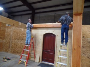 two guys on ladders building a display, making great progress, log homes, log cabin homes, log cabins, post and beam homes, timberframe homes, timber frame homes, laminated logs, engineered logs, floor plan designs, kiln dried logs, Timberhaven local reps, log homes in Pennsylvania, log homes in PA, Timberhaven Log Homes, Timberhaven Log & Timber Homes