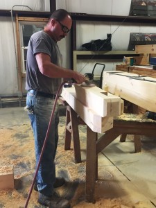 man sanding white pine timber frame wooden member, hammer truss, log homes, log cabin homes, log cabins, post and beam homes, timberframe homes, timber frame homes, laminated logs, engineered logs, floor plan designs, kiln dried logs, Timberhaven local reps, log homes in Pennsylvania, log homes in PA, Timberhaven Log Homes, Timberhaven Log & Timber Homes