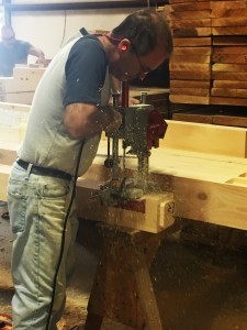 man using machine on white pine timber, timber frame hammer truss, hammer truss, log homes, log cabin homes, log cabins, post and beam homes, timberframe homes, timber frame homes, laminated logs, engineered logs, floor plan designs, kiln dried logs, Timberhaven local reps, log homes in Pennsylvania, log homes in PA, Timberhaven Log Homes, Timberhaven Log & Timber Homes