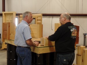 two men talking by log demonstration table, educational seminar, log homes, log cabin homes, log cabins, post and beam homes, timberframe homes, timber frame homes, laminated logs, engineered logs, floor plan designs, kiln dried logs, Timberhaven local reps, log homes in Pennsylvania, log homes in PA, Timberhaven Log Homes, Timberhaven Log & Timber Homes