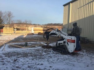 man using a machine to dig footers, product display areas, timber frame display, timber frame pavilion, timber frame outdoor wooden structures